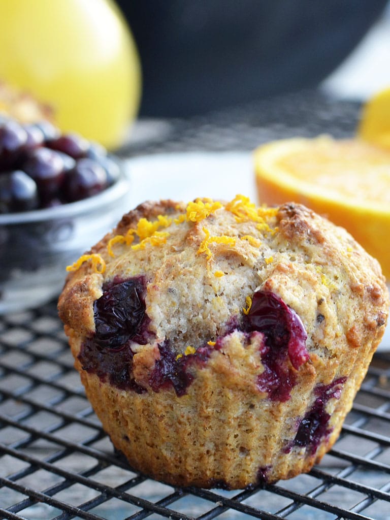 whole wheat orange blueberry muffin with blueberries and an orange in the background