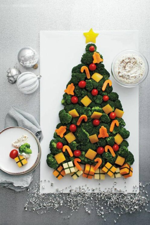 Broccoli tree topped with carrots cut into ornament shapes on a white platter