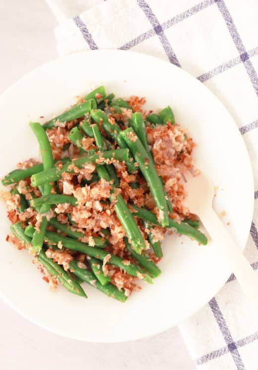 green bean casserole portion on a white plate with a blue checkered cloth underneath