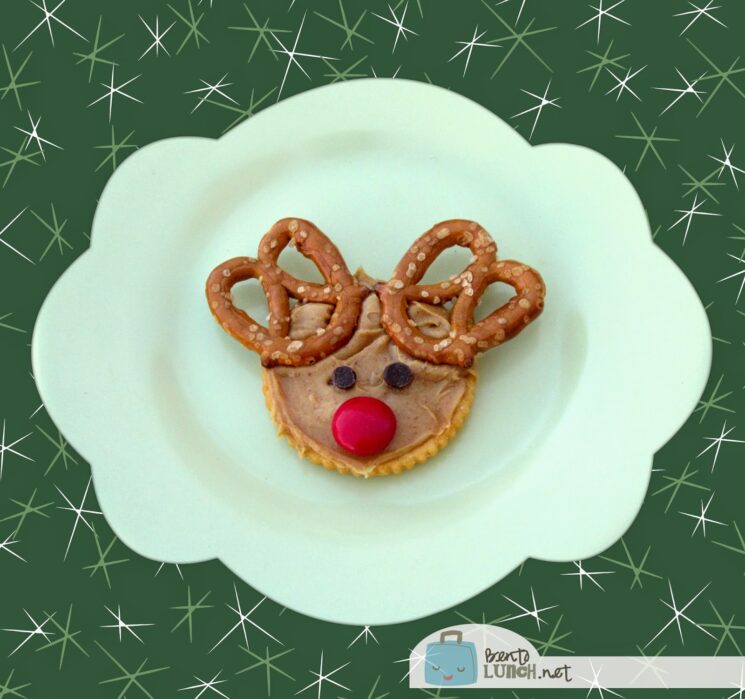 Crackers topped with peanut butter and antlers made of pretzels and a red candy nose