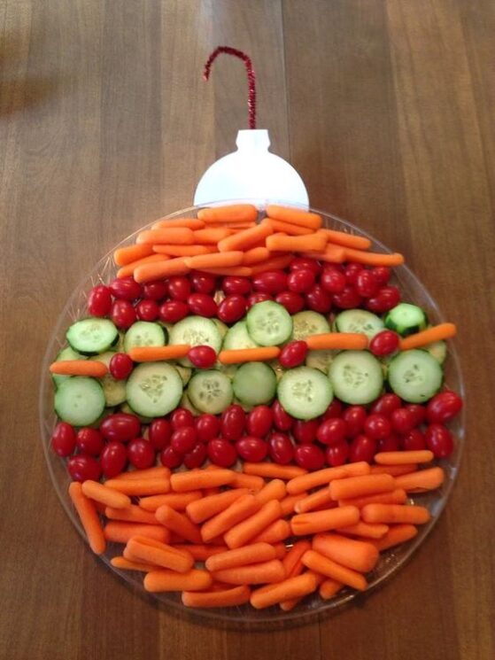 A round plate with carrots and tomatoes in stripes topped with a pipe cleaner to make an ornament