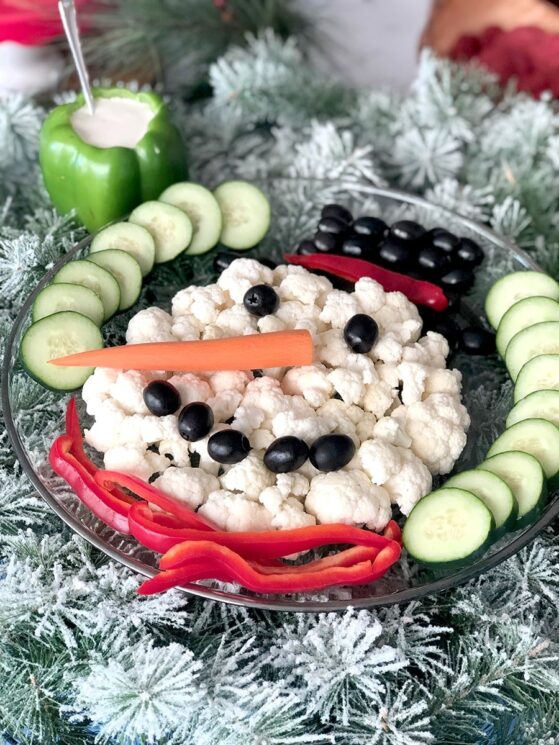 snowman face made with cauliflower florets with a carrot nose and olive smile