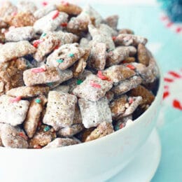 christmas puppy chow in a white bowl with christmas sprinkles