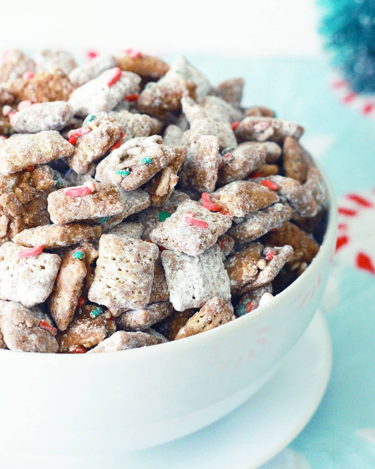 christmas puppy chow in a white bowl with christmas sprinkles