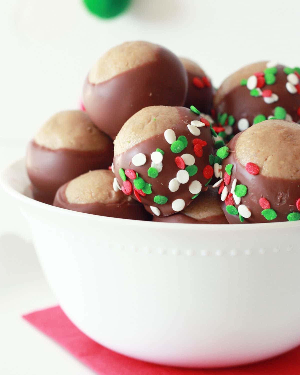 Holiday Buckeyes in a white bowl with festive christmas sprinkles