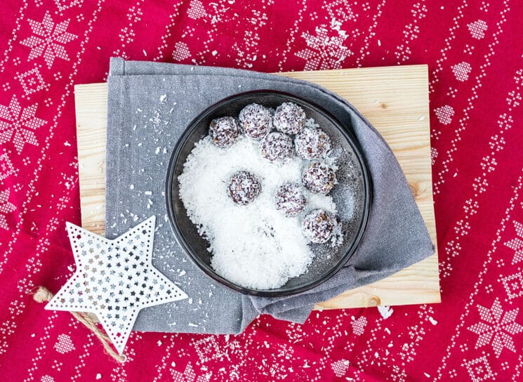 no bake snowball energy balls for santa in a bowl with coconut on top a wood board with a white star and a red christmas cloth