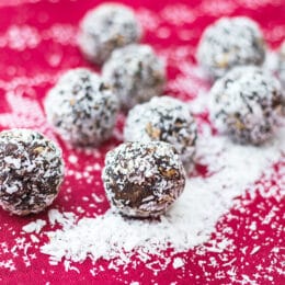 no bake snowball energy balls with coconut on a festive red christmas cloth and extra coconut scattered