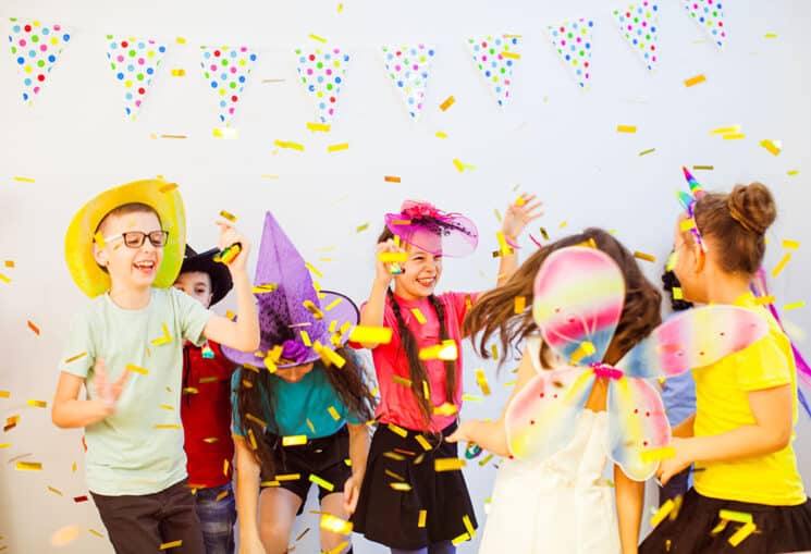 Excited happy children dancing at a party. Kids enjoying glitter confetti. Kids festive entertainment