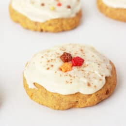 soft pumpkin cookies on a white tray with leaf sprinkles and maple frosting