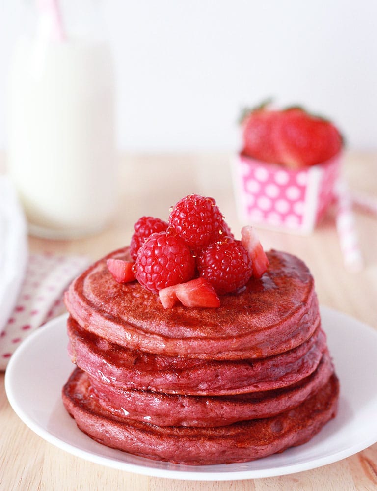 stack of dye free pink pancakes with raspberries and strawberries on top