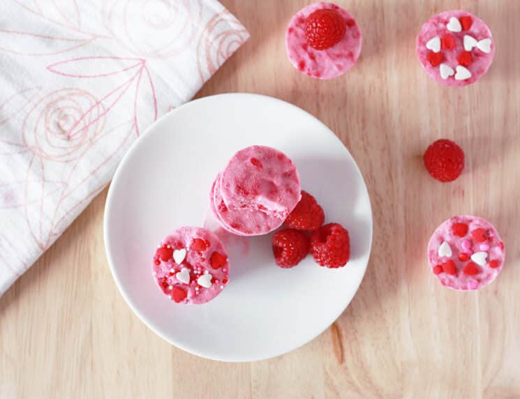 Top view of raspberry-frozen yogurt bites with colorful sprinkles and fresh raspberries