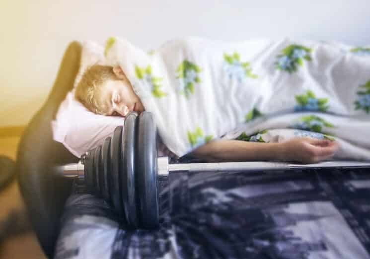 sleeping teenager with weights in front of him