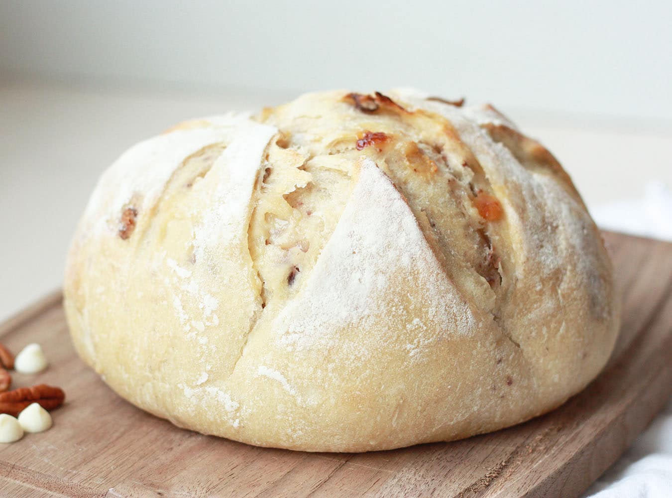 white chocolate pecan sourdough loaf on a wood cutting board