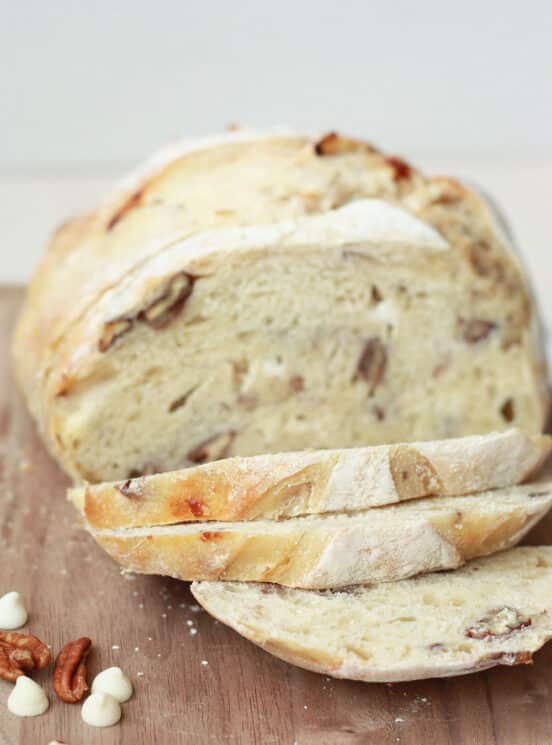 white chocolate pecan sourdough bread sliced on a wood cutting board