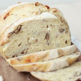 white chocolate pecan sourdough bread sliced on a wooden cutting board