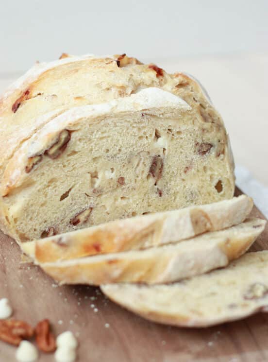 white chocolate pecan sourdough bread sliced on a wooden cutting board
