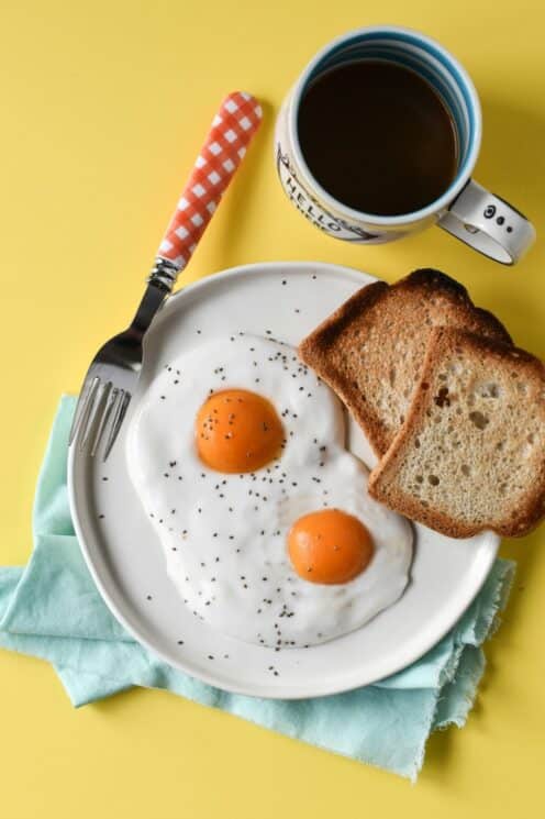 yogurt and apricot halves designed to look like a sunny up egg on a yellow background with a mug of juice