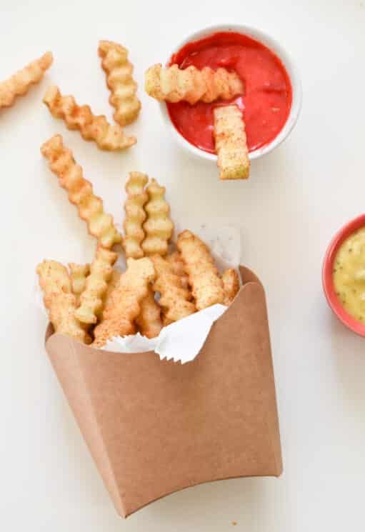 apples cut into fry shapes in a fry container and jam in a dipping bowl