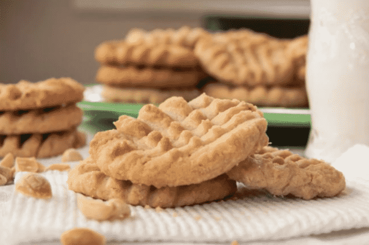 a stack of peanut butter cookies with a glass of milk on a green plate