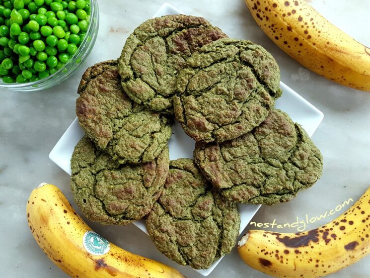 green cookies on a white plate with a bowl of peas and bananas in the background