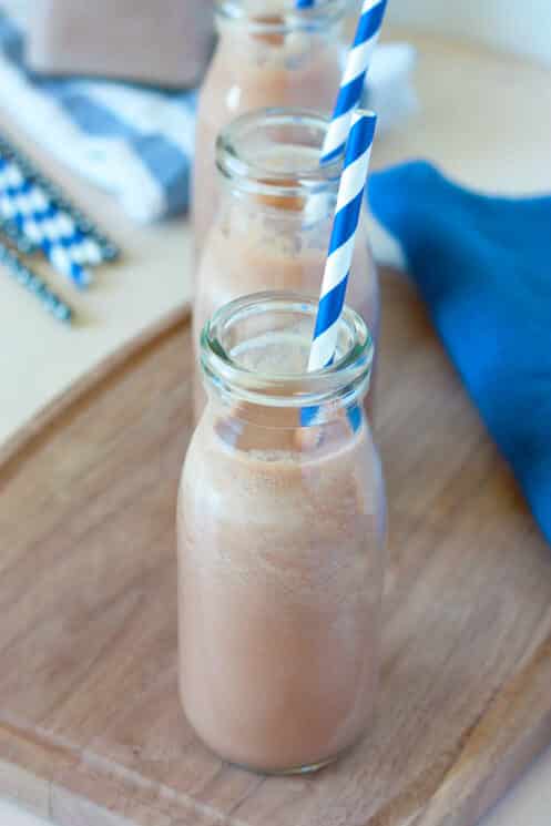 view of 3 bottles of homemade chocolate milk in a row with blue and white striped straws