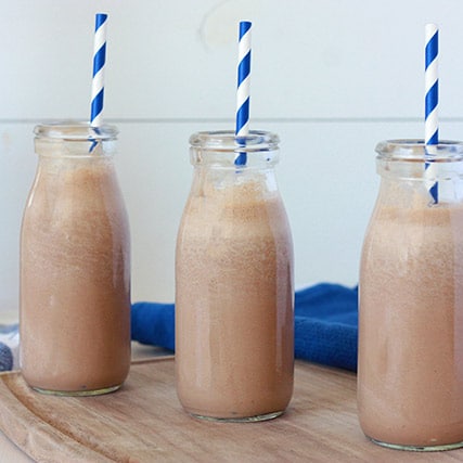 3 milk bottles of chocolate milk with blue and white striped straws