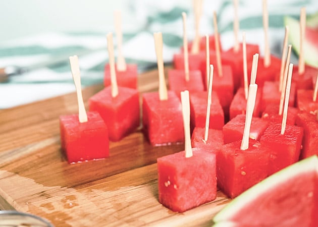 Watermelon cubes on a wooden cutting board with popsicles