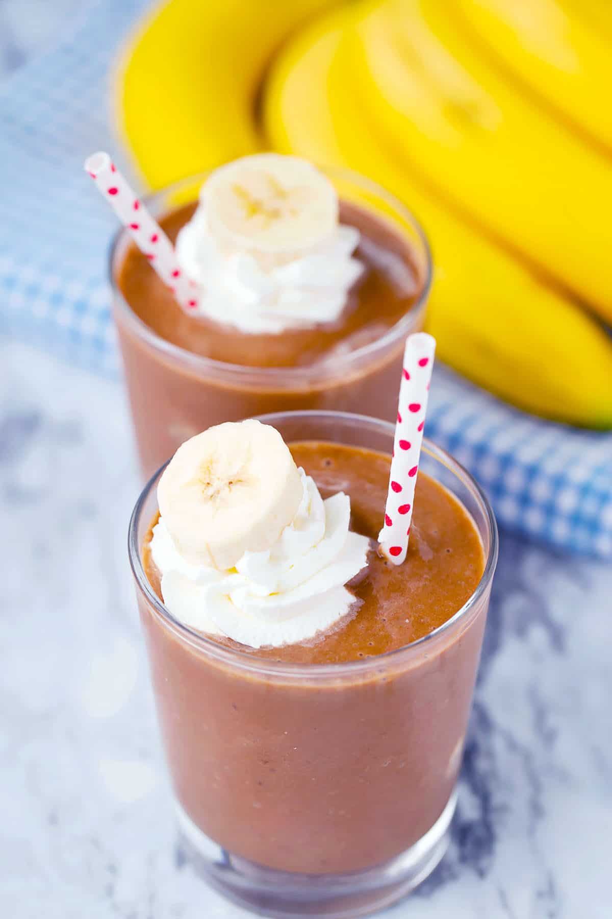 chocolate banana smoothie with bananas and whip cream on top with a polka dot straw