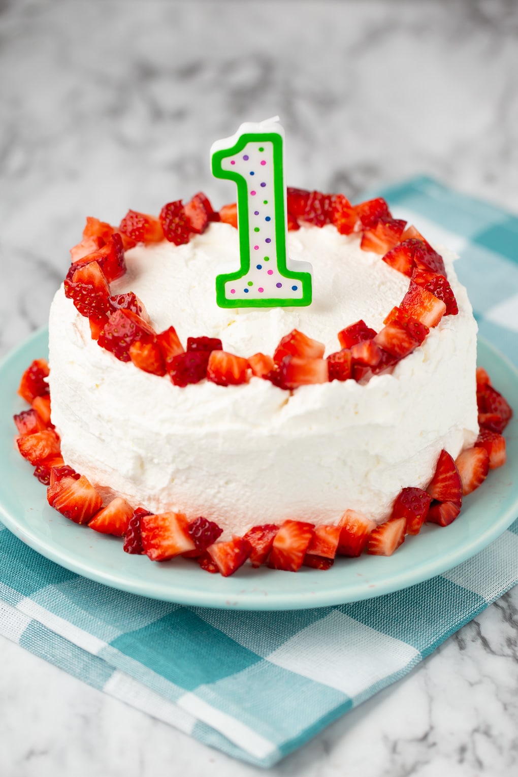 smash cake for first birthday with strawberries and whipped frosting