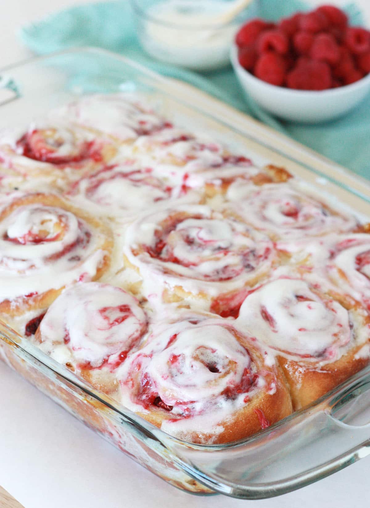 glass baking dish of raspberry rolls with vanilla glaze