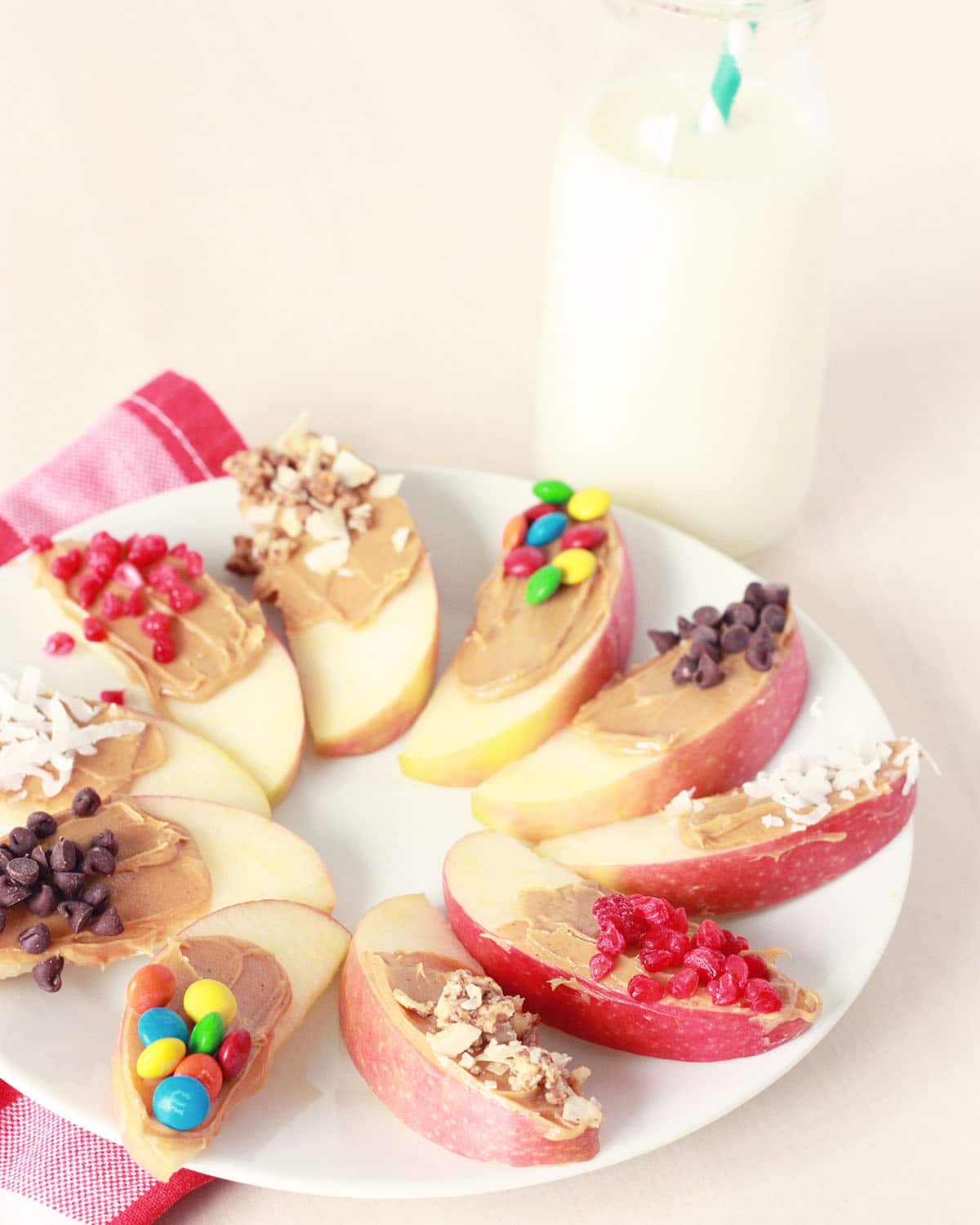 apple snack with sliced apples and peanut butter and a variety of toppings on a white plate