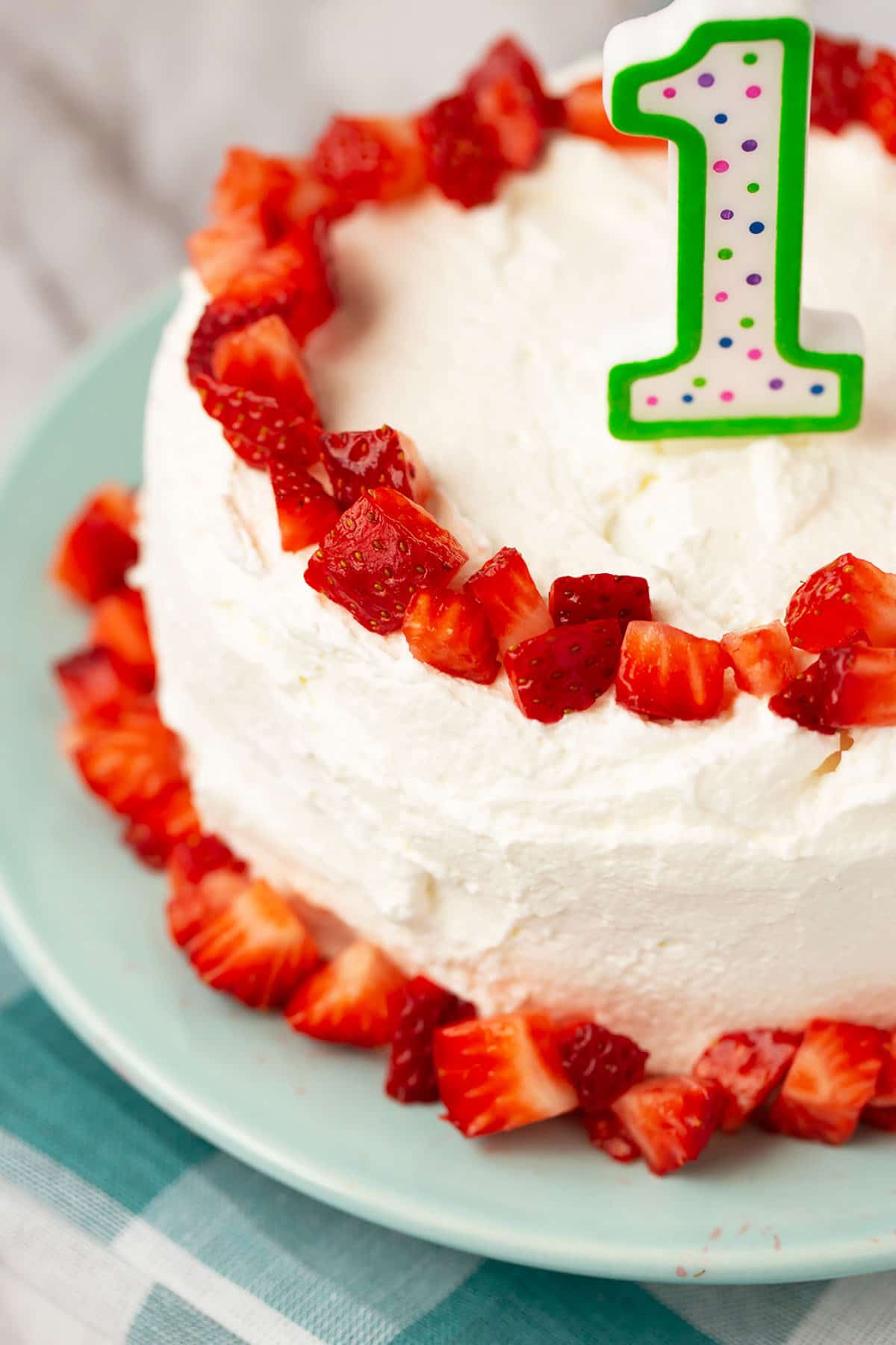 healthy smash cake sweetened with fruit and decorated with fresh strawberries and a candle