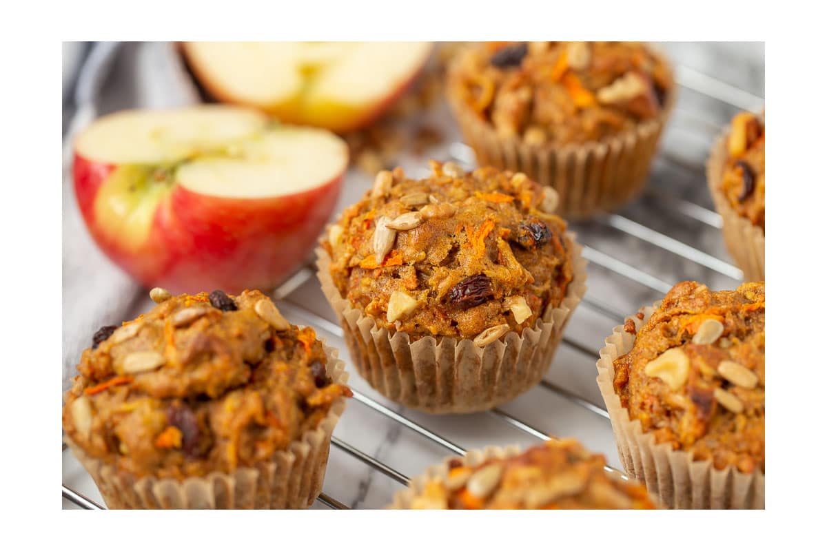 morning glory muffins on a cooling rack with apples in the background