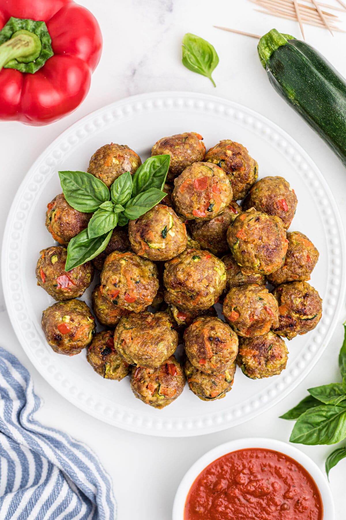 healthy chicken meatballs on a white plate with fresh basil