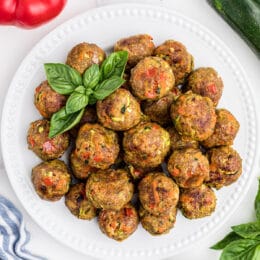 baked chicken meatballs on a white plate with marinara sauce in bowls