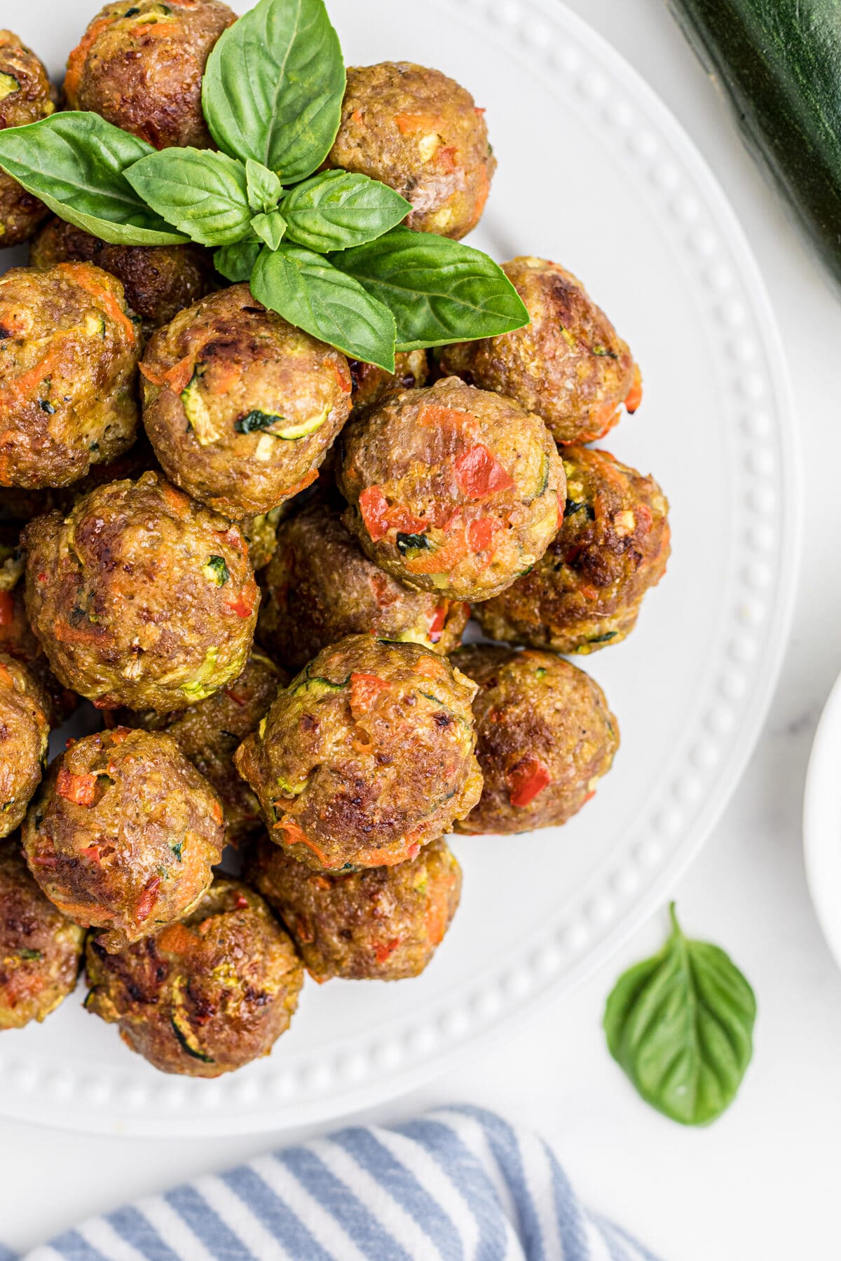 healthy baked chicken meatballs on a plate with fresh basil on top