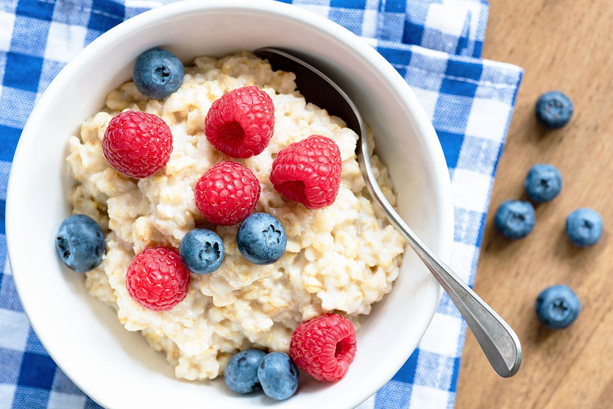 Oatmeal with fresh berries, raspberry and blueberry. Closeup view, top view with wood background. Healthy eating, healthy breakfast.