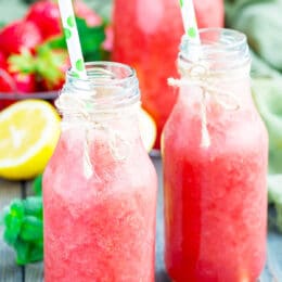 Homemade strawberry lemonade with fresh strawberry, lemon, ice and mint in glass bottle, vertical