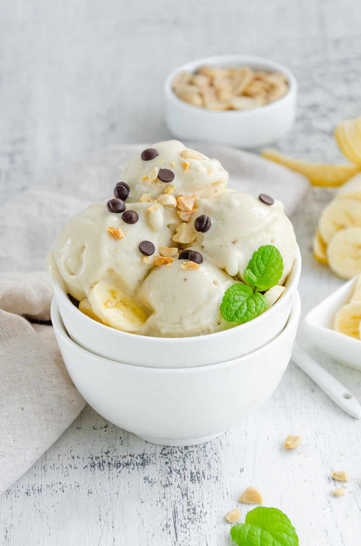 Homemade banana ice cream in a bowl with peanuts and chocolate on a wooden background. Healthy dessert. 