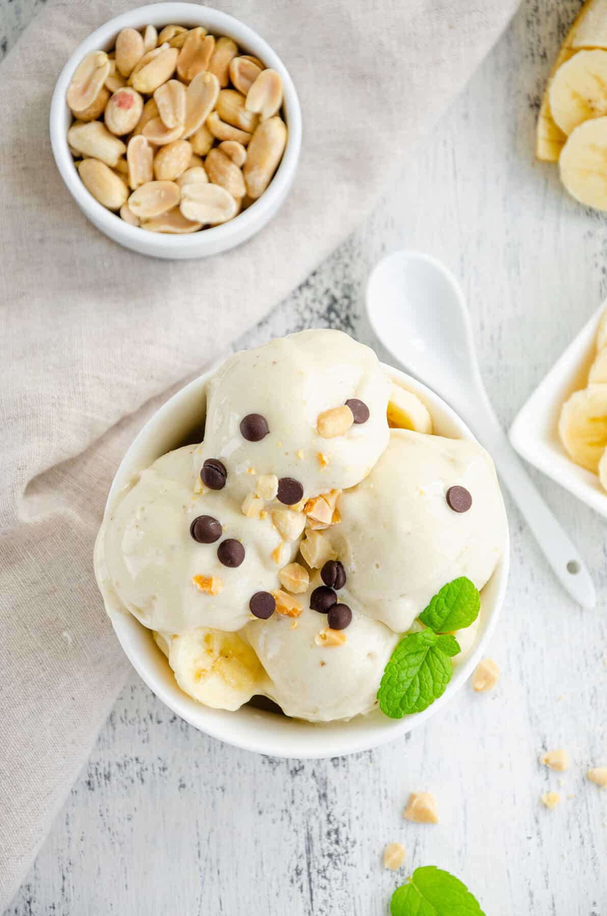One ingredient banana ice cream in a bowl with peanuts and chocolate on a wooden background. Healthy dessert. 