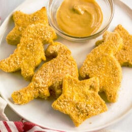 kid-friendly homemade chicken nuggets in star and dinosaur shapes on a plate with dipping sauce