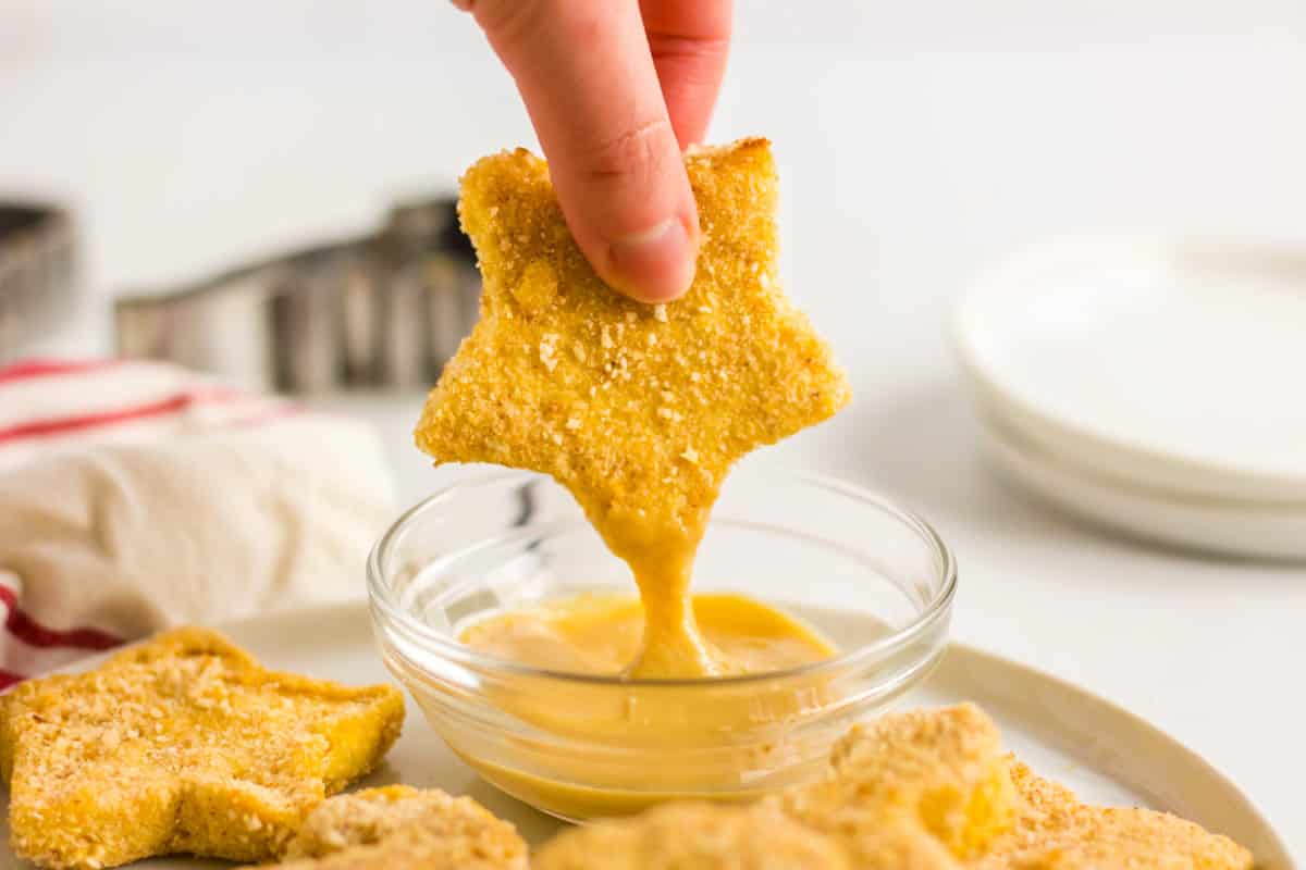 kid-friendly homemade chicken nugget in a star shape being dipped into sauce