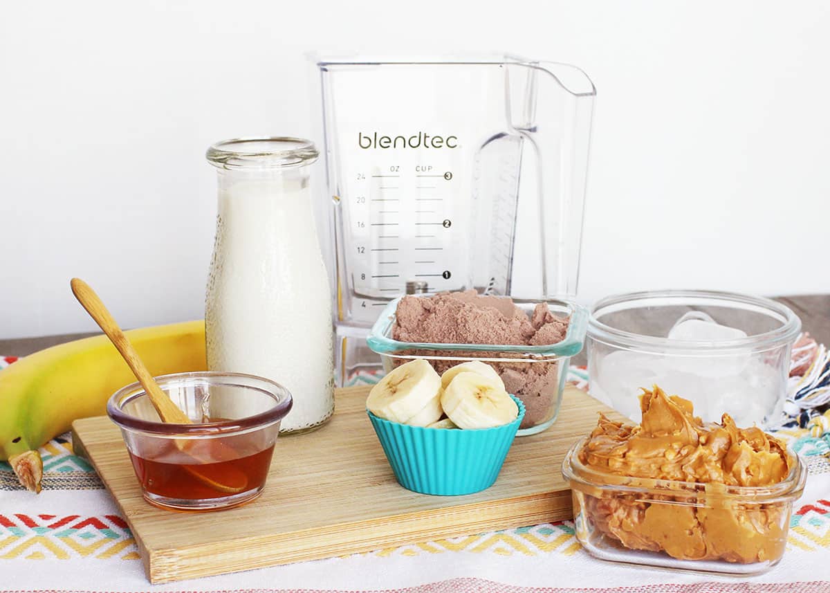 ingredients for peanut butter banana smoothie - bananas, peanut butter, milk, chocolate protein powder, honey, ice.