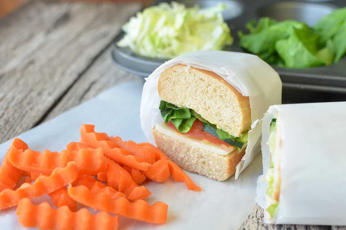 homemade sub sandwich for kids wrapped in white paper with carrot sticks