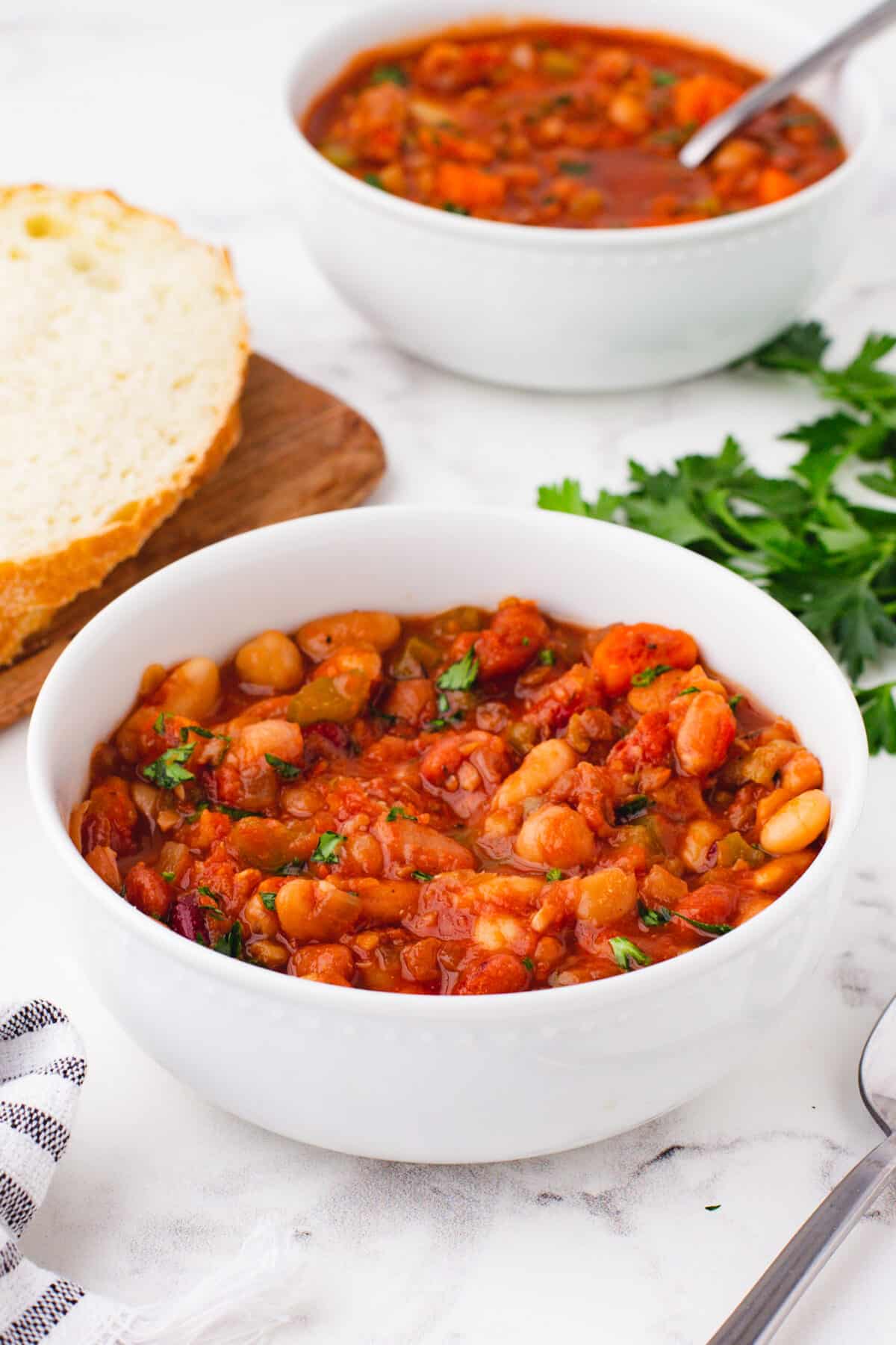 15 bean soup in a white bowl with fresh herbs in the background