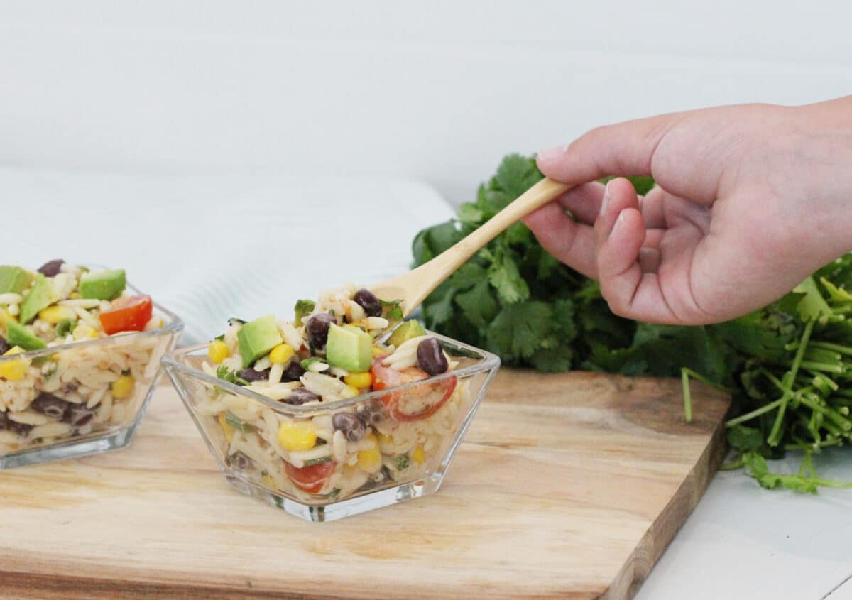 two bowls of avocado salad on a wooden cutting board