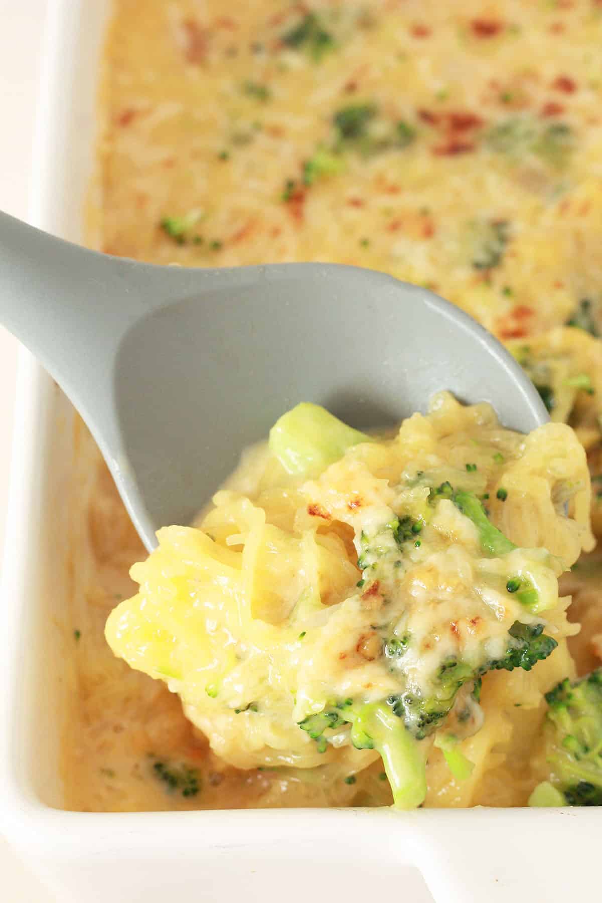 A big scoopful of cheesy butternut squash with broccoli in a serving dish