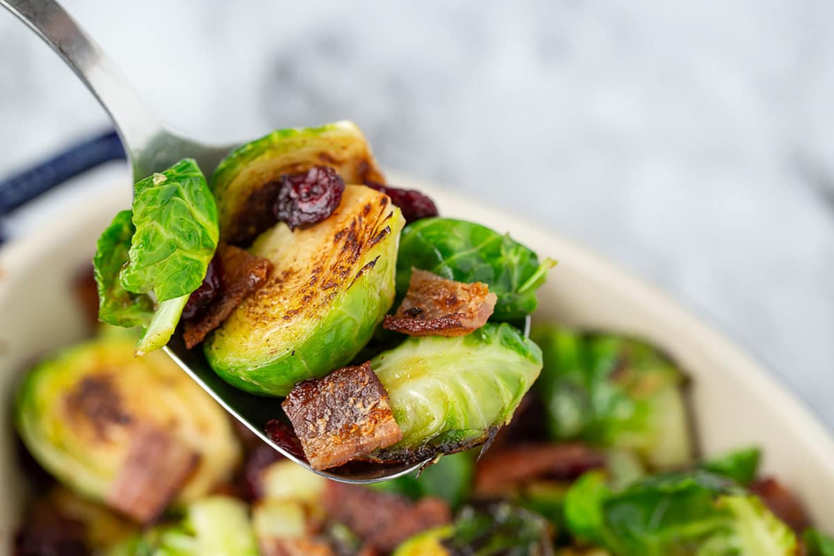 close up brussels sprouts with bacon, cranberries and honey