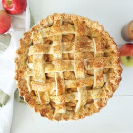 caramel apple pie with a lattice crust overhead shot with apples in the background