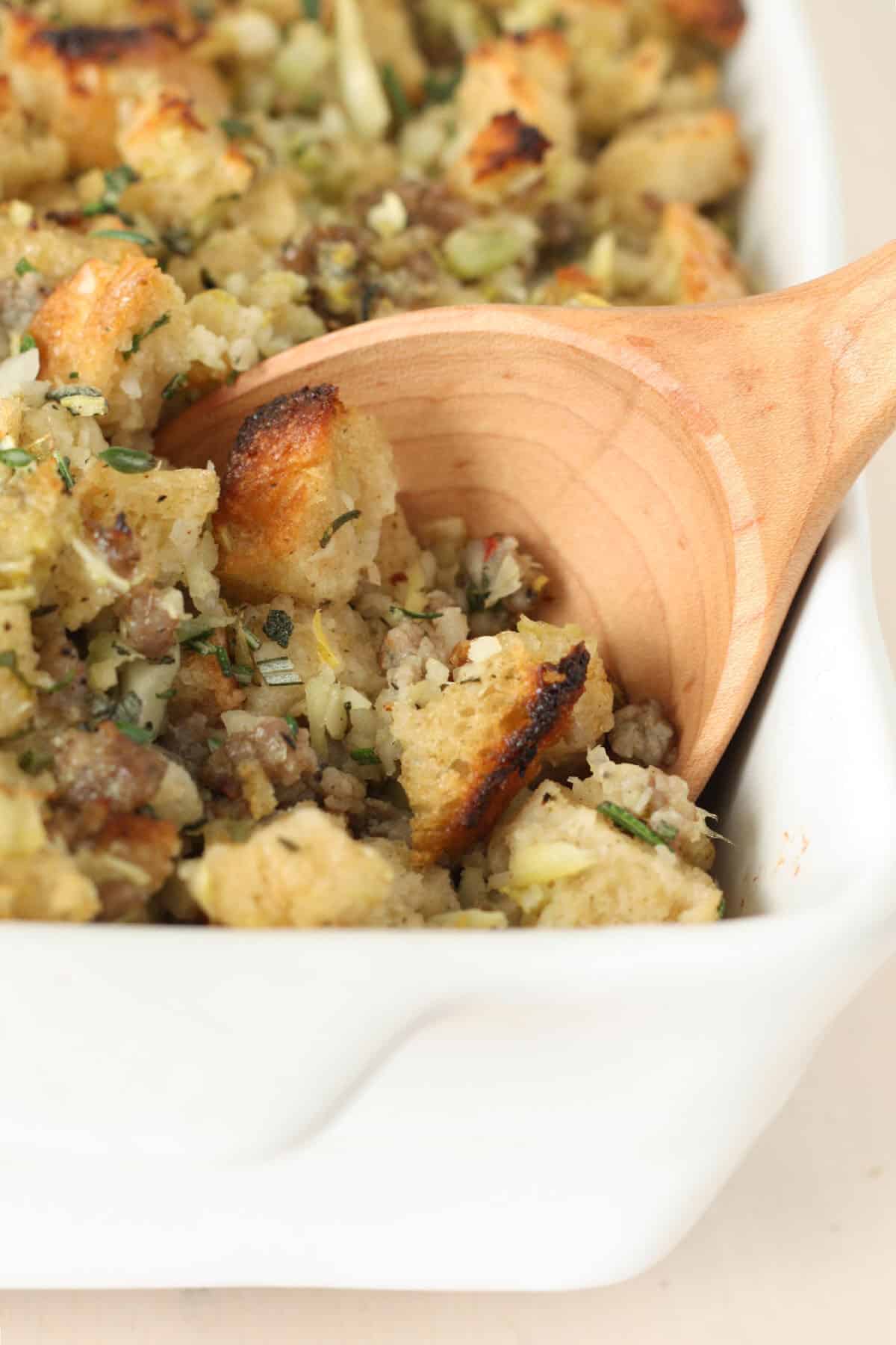 homemade stuffing being scooped out with a large wooden spoon